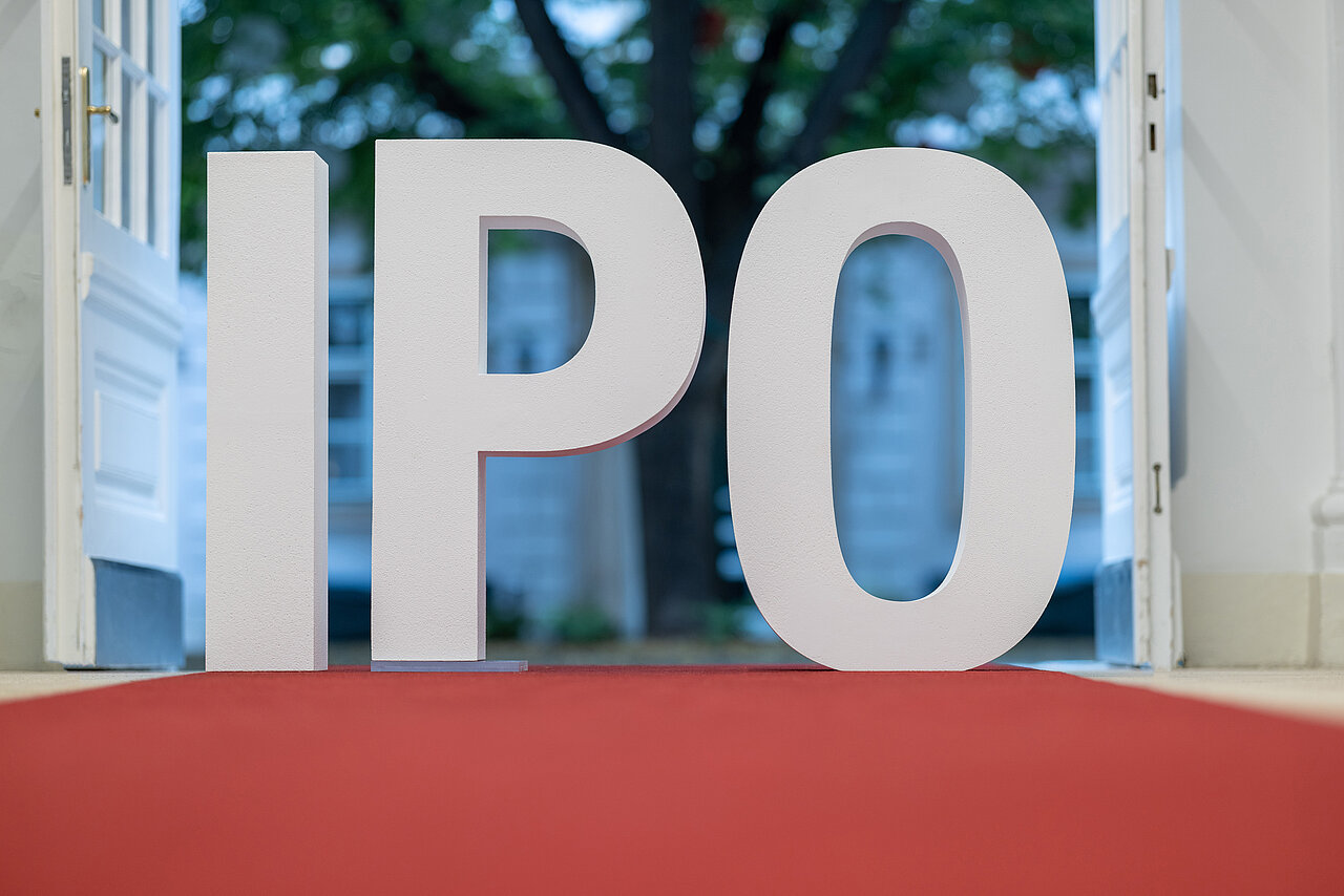IPO-Schriftzug im Eingangsbereich der Wiener Börse mit Hof und Baum im Hintergrund